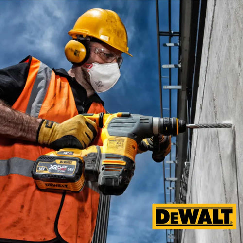 A construction worker wearing a hard hat, ear protection, and a mask uses a rotary hammer drill with DEWALT Extreme SDS Plus 2-Cutter Drill Bits on a concrete wall.