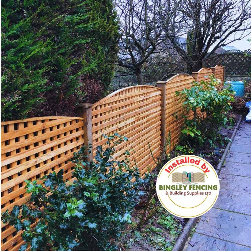 Load image into Gallery viewer, An Arched Chequerboard Trellis Panel from Bingley Fencing borders a garden path lined with green shrubs. Ideal for climbing plants, the image features a round logo that says Installed by Bingley Fencing & Building Supplies LTD.