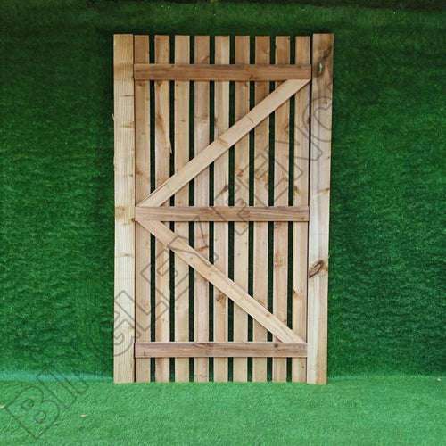 A Bingley Fencing Paling Gates Single Sided 1" Gaps- Flat Top & Arched Top stands against a green backdrop. Its natural wood texture contrasts sharply with the lush color, highlighting both its design and the meticulous installation that minimizes privacy gaps.