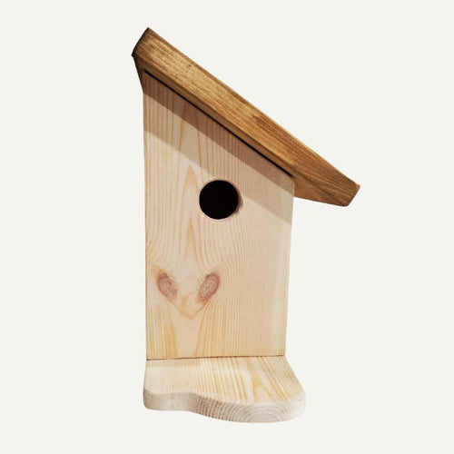 The Tall Bird House by Bingley Fencing is handmade with a unique design, slanted roof, circular entrance hole, and small flat base. Displayed against a plain, light background.