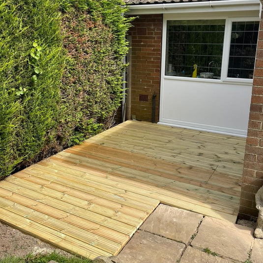 Small wooden decking are infront of a kitchen window