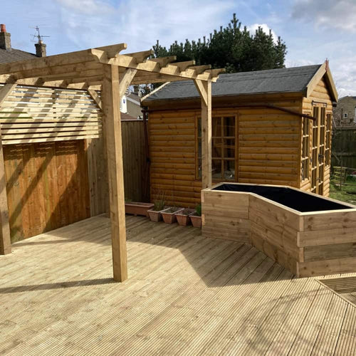 A wooden garden deck with a pergola, a raised planter, several empty plant pots, and a wooden shed in the background under a partly cloudy sky.