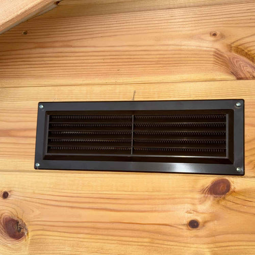 The Bingley Fencing Shed Air Vents (Louvre Vent with Fly Screen) in black metal are mounted on a natural wood wall, offering essential ventilation for your garden building while keeping bugs out.