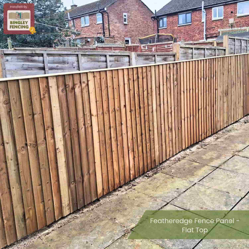 Load image into Gallery viewer, A Bingley Fencing Featheredge Fence Panel - Flat Top creates privacy fencing alongside a paved patio, separating brick house backyards, with other fences visible in the background.