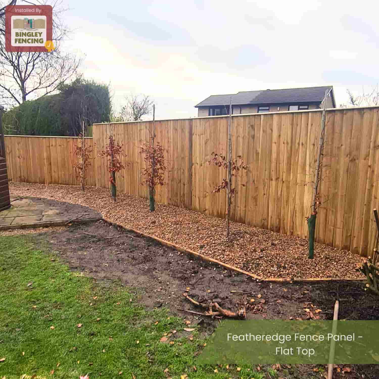 A garden bordered by Bingley Fencing Featheredge Fence Panels - Flat Top surrounds a mulched area with young trees, while grass and a path appear in the foreground. The Bingley Fencing logo is in the corner.