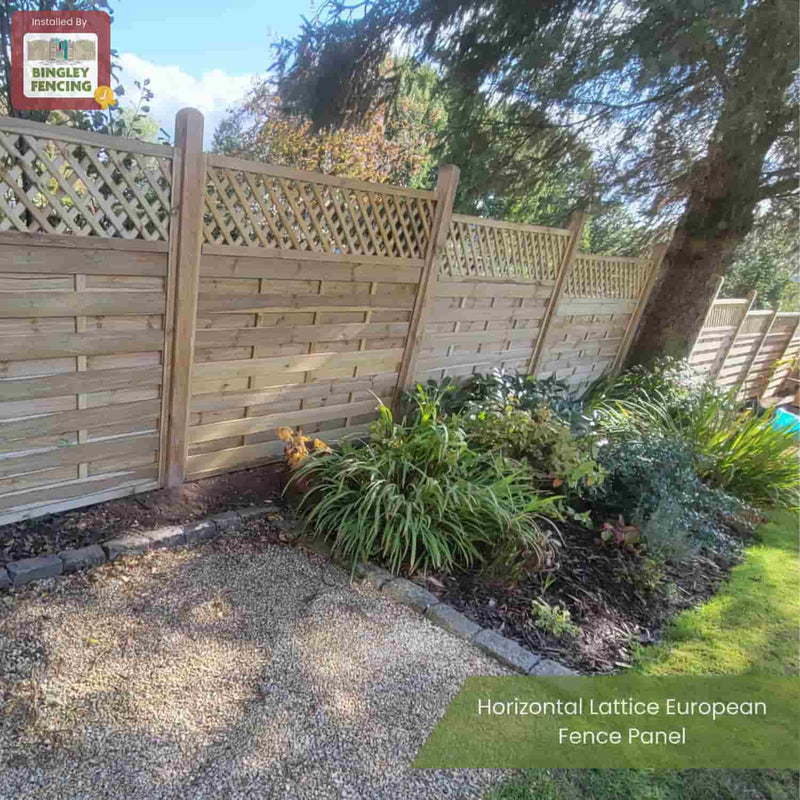 Load image into Gallery viewer, A KDM Horizontal Lattice European Fence Panel separates a planted garden bed from a gravel path, with sunlight filtering through trees. A KDM sign is visible in the top left corner of these stylish privacy panels.