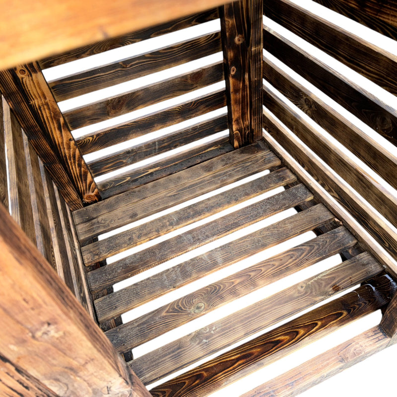 Load image into Gallery viewer, The empty interior of Bingley Fencings Unique Log Store features darkly stained, rugged wooden slats with a rustic charm. Light filtering through highlights the timber grain and spaces between the slats, creating a captivating effect. All sizes available.