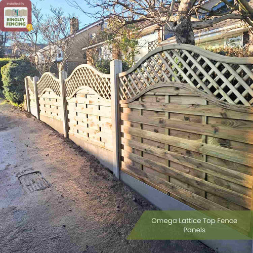 A decorative timber fence with a curved omega lattice top, the KDM Omega Lattice Top Fence Panels (OLT), lines a sunlit residential street, adding elegance to gardens with its vertical posts and graceful design.