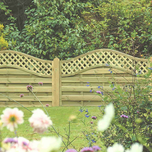 The KDM Omega Lattice Top Fence Panels (OLT) feature decorative timber and lattice accents, beautifully bordered by green shrubs and blooming flowers in the foreground.