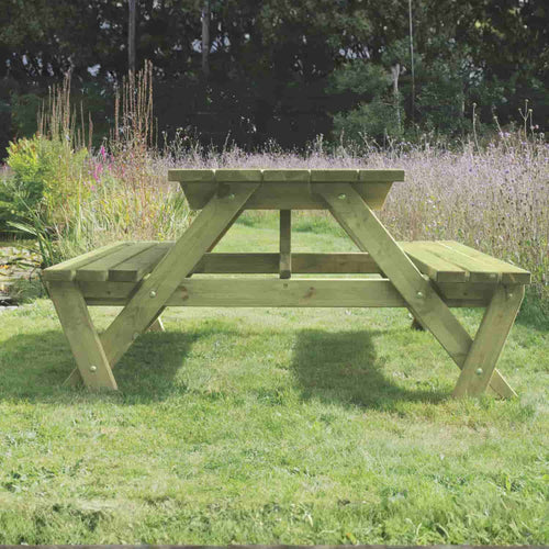 The KDM Premium A Frame Table 150cm x 180cm (PB180) stands on a grassy lawn, bordered by European style fence panels and surrounded by colorful wildflowers and lush greenery in a charming garden.