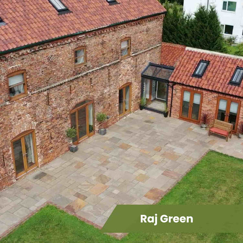A large brick house with a red-tiled roof and glass entry features a spacious patio made from Bingley Fencing’s Indian Sandstone Paving Project Pack, surrounded by a green lawn. Text overlay: Raj Green.