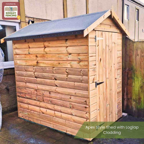 A Bingley Fencing sign marks a wooden shed with Loglap Cladding Boards (Various Thicknesses) from Bingley Fencing, showcasing an apex-style roof, single door, and felt top beside a fence and wall on a paved area.