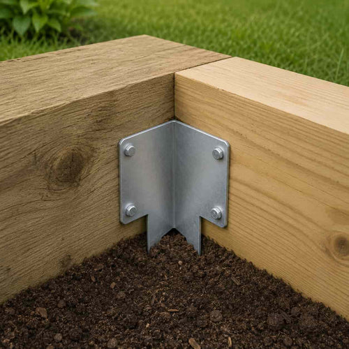 The John George Internal Corner Support Spike for Sleepers securely joins two wooden beams at a right angle above soil and grass, reinforcing outdoor corners with strong galvanised steel and screws.