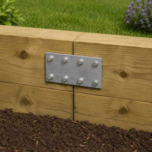 The John George Sleeper Support Plate for Timber Sleepers, secured with six screws, fastens two wooden boards in a garden bed, ensuring sturdy sleeper support with soil and grass visible below.