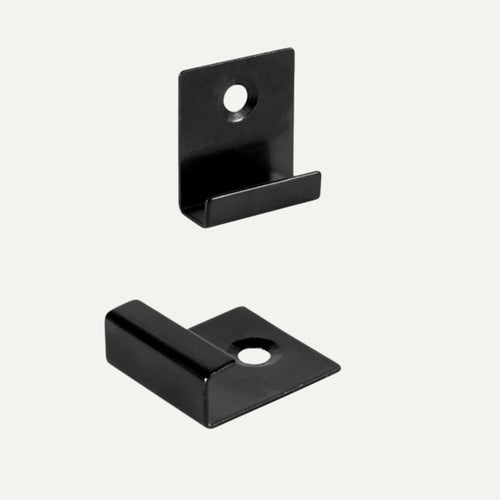 Two black metal deX Classic Composite Decking Starter Clips, each featuring an L-shape and a single screw hole in the flat base for composite decking.