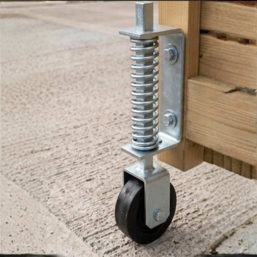 A close-up of the KDM Hiatt Heavy Duty Spring Loaded Gate Wheel 14" mounted on a wooden frame, shown on a textured concrete surface.