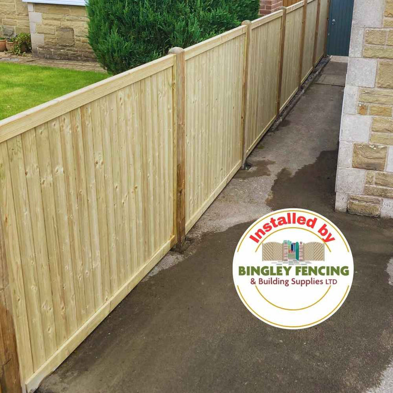 Load image into Gallery viewer, Tongue & Groove European Fence Panels Flat Top by KDM create a long wooden privacy fence that lines a paved pathway, running alongside a grassy area with shrubs. In the corner of the image, there's a circular logo that reads installed by Bingley Fencing & Building Supplies LTD.
