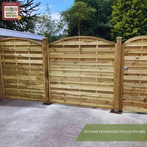 The KDM Arched Horizontal Fence Panel (AH180) features wooden horizontal slats and an arched top, supported by vertical posts on concrete, with trees and shrubs behind. Text reads “Arched Horizontal Fence Panels” and “KDM.”.