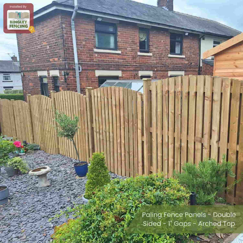 Load image into Gallery viewer, Bingley Fencing’s Paling Fence Panels - Double Sided with 1 gaps and an arched top separate a garden of plants and gravel from a brick house and shed, with a birdbath and potted plants in the foreground.