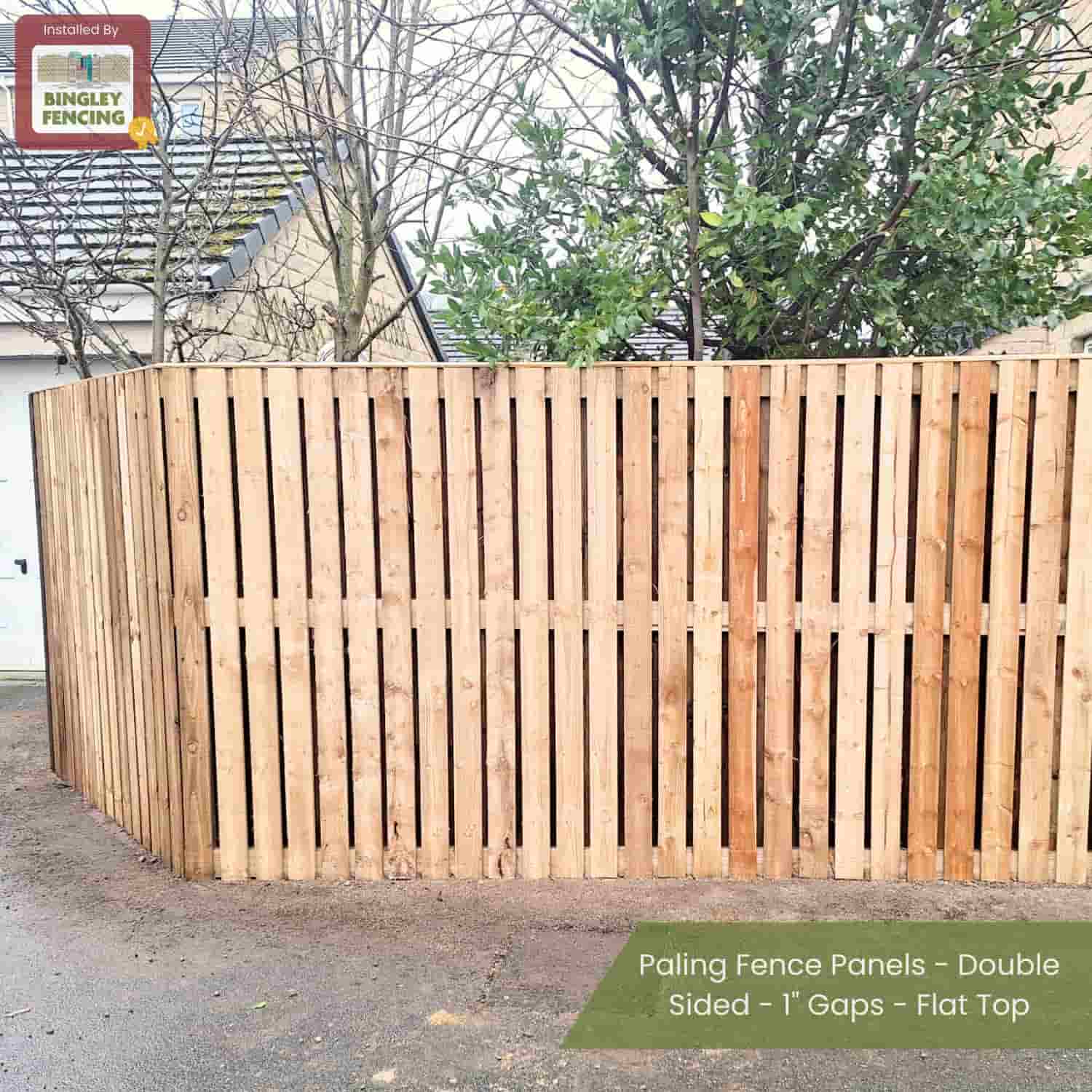 A yard with trees is enclosed by Bingley Fencing’s Paling Fence Panels—Double Sided, 1 Gaps, Flat Top—made of pressure-treated wood. The tall fence stands in front of a house with a gray roof.
