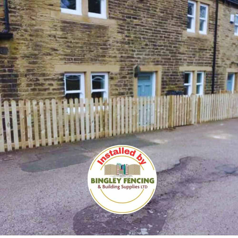 Load image into Gallery viewer, A stone house with a light blue door is surrounded by recently installed Paling Fence Panels, featuring single-sided construction and 2" gaps with a flat top. The logo in the foreground reads Installed by Bingley Fencing.