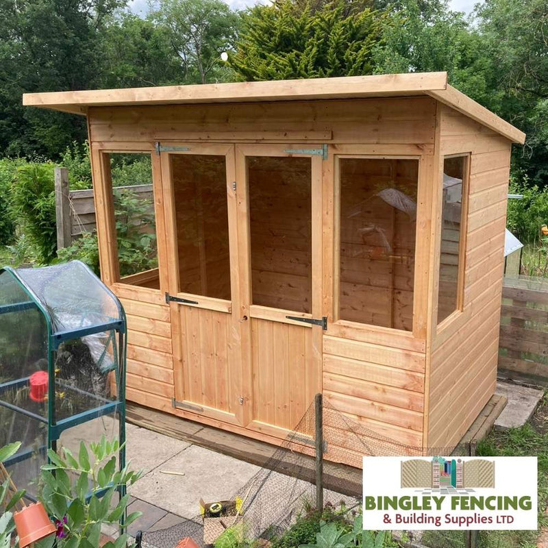 Load image into Gallery viewer, A Pent Summerhouse with spacious glass windows and a door showcases itself elegantly as part of Bingley Fencing's collection. Nearby, plants flourish in the greenhouse while trees and fencing complete the picture. A logo in the bottom right corner says Bingley Fencing & Building Supplies LTD, providing reassurance through their convenient payment plan option.