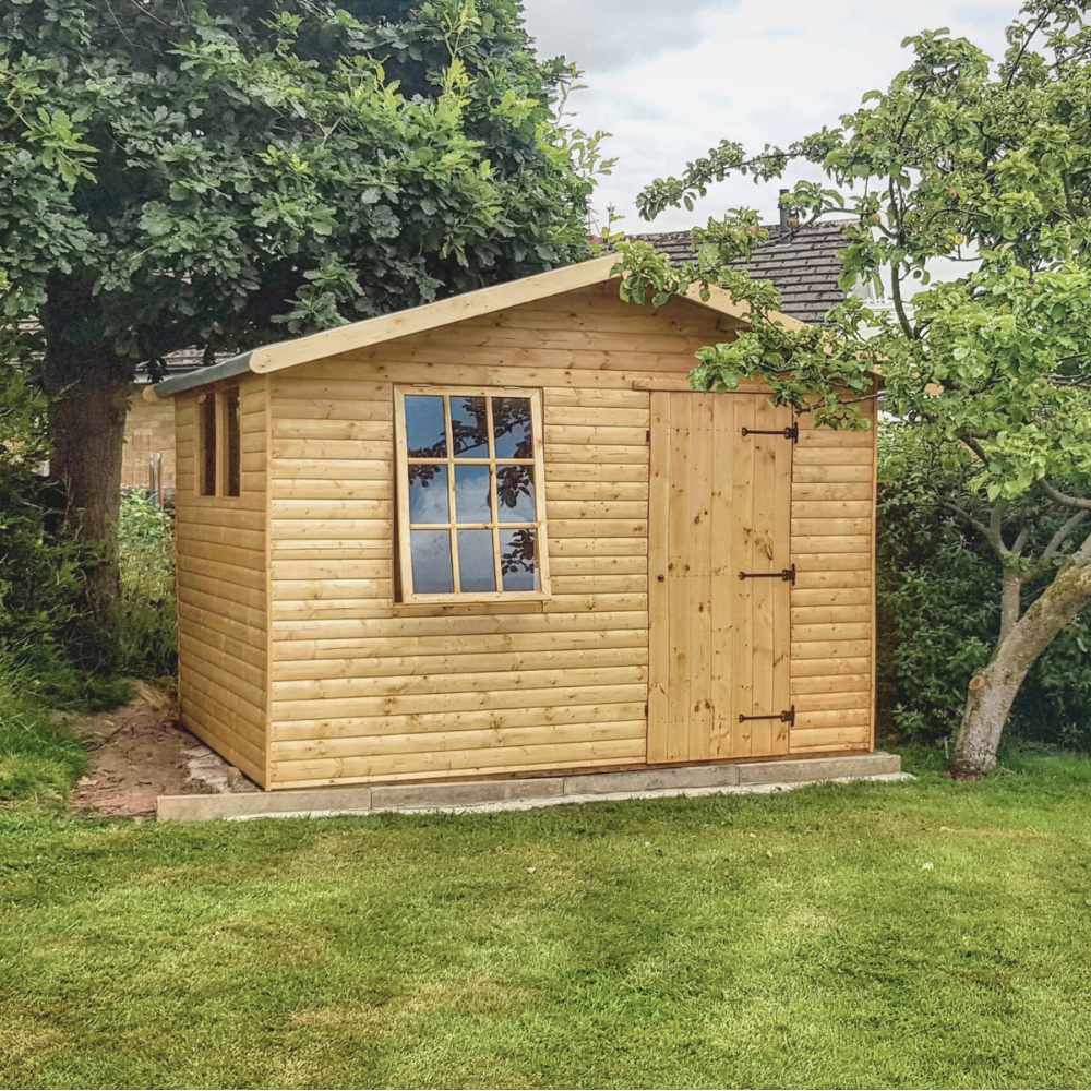 Hobby house style garden shed with open georgian window. Surrounded by trees.