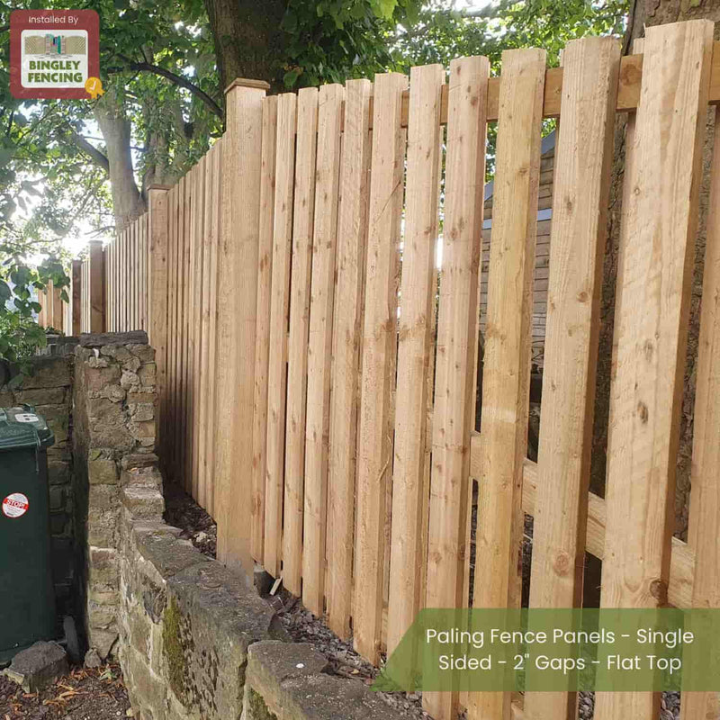 Load image into Gallery viewer, Bingley Fencing’s Double Sided Paling Fence Panels with 2 gaps and flat tops installed beside a stone wall in a leafy outdoor space. Green bin, dense trees visible; text overlay highlights installation details.