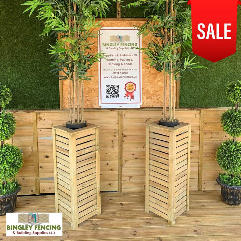 Load image into Gallery viewer, Two KDM Reduced Tall Slatted Square Planters, each holding potted bamboo, are shown against a wooden fence. A ‘SALE’ banner appears in the top right corner, with a Bingley Fencing sign on the back wall.