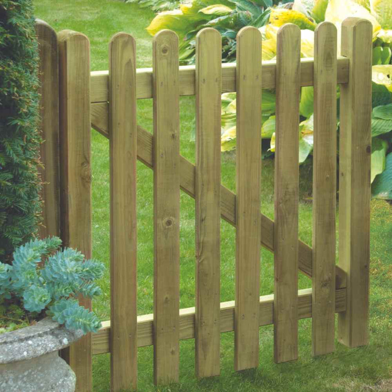 Load image into Gallery viewer, The Premium Round Top Picket Gate – PPG90 by KDM, surrounded by lush greenery, features vertical slats with rounded tops and diagonal support bars, adding rustic charm to the landscape.