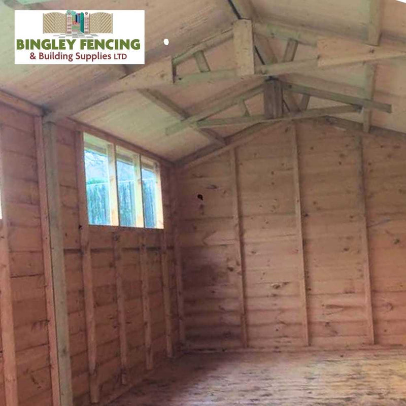 Load image into Gallery viewer, Interior view of The Workshop - Speciality Shed, featuring unfinished wooden walls and a pitched roof. Sunlight streams through the row of windows on the left. A logo in the top corner reads, Bingley Fencing. This customizable shed offers both versatility and style for your projects.