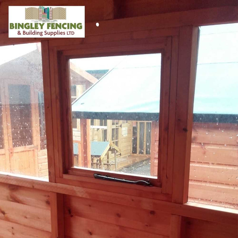 Load image into Gallery viewer, From the interior of The Workshop - Speciality Shed, you can gaze out through the window at additional wooden structures. The Bingley Fencing sign is prominently displayed in the top left corner, assuring you of all resources required for your workshop shed or customizable shed project.