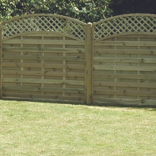 The KDM Arched Lattice Top Panels - ALT180 wooden fence, with vertical boards, stands gracefully on a well-maintained grassy lawn. Tanalised for durability and surrounded by trees and greenery, it basks in bright sunlight to create an enchanting outdoor space.