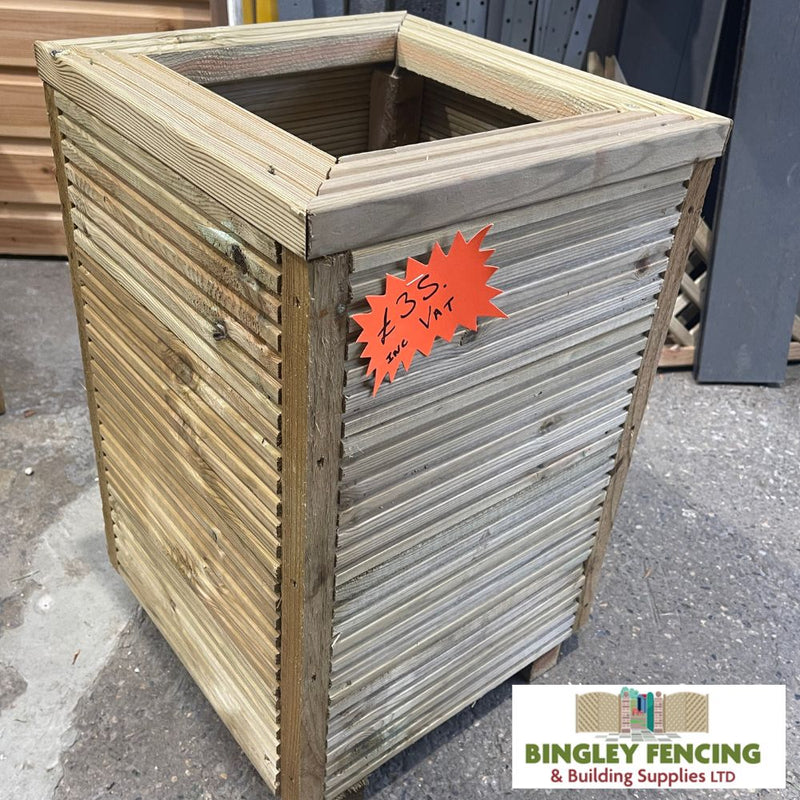 Load image into Gallery viewer, A KDM Bingley Fencing Tall Planter, expertly crafted from moisture-resistant tanalised timber, rests on a warehouse floor. A price tag of £35 is attached to one side, and a Bingley Fencing & Building Supplies Ltd sign is visible in the bottom right corner.
