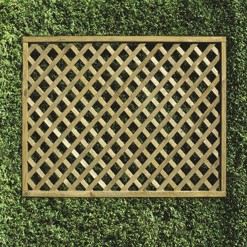 The KDM Trellis - Heavy Diamond Lattice, Rectangle 120cm x 180cm (HDL11), is placed against lush green shrubbery. The pressure-treated wooden panel with its diagonal grid serves as a large privacy trellis, creating a contrasting backdrop with the vibrant greenery.