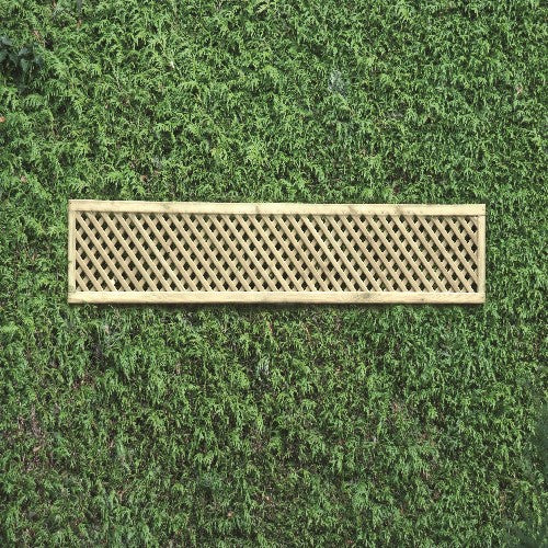 A rectangular KDM Trellis - Privacy Lattice, measuring 30cm x 183cm, is mounted on a lush, green hedge. The trellis's crisscross pattern stands out against the dense foliage, creating a striking contrast.