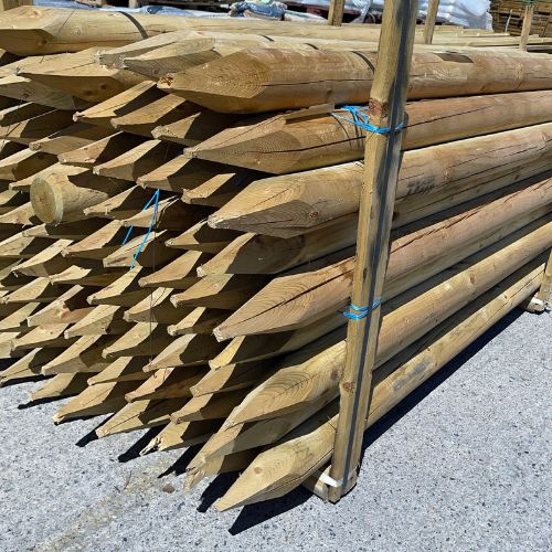 A stack of Bingley Fencing Tree Stake - Machine Round Spiked Fence Posts, measuring 3” x 8ft, is neatly arranged on a concrete surface. Resembling sturdy tree stakes, these tanalised treated wood posts with pointed ends are bound together with blue ties, ready for transport or use in a construction project.