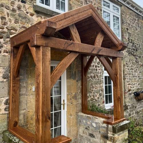 Large instricate oak porch with cross members and beams on a stone house