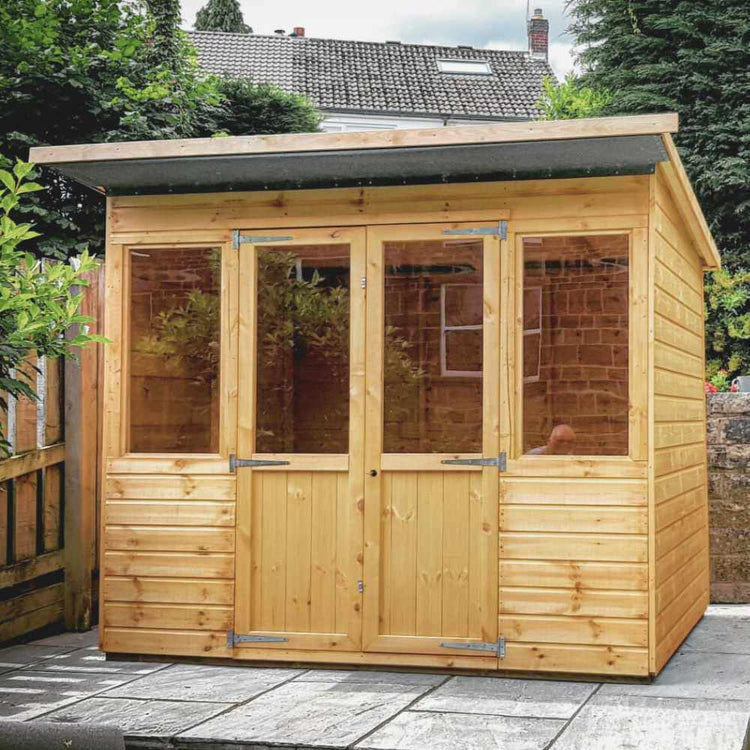 Pent style summerhouse with double doors sat on a garden patio