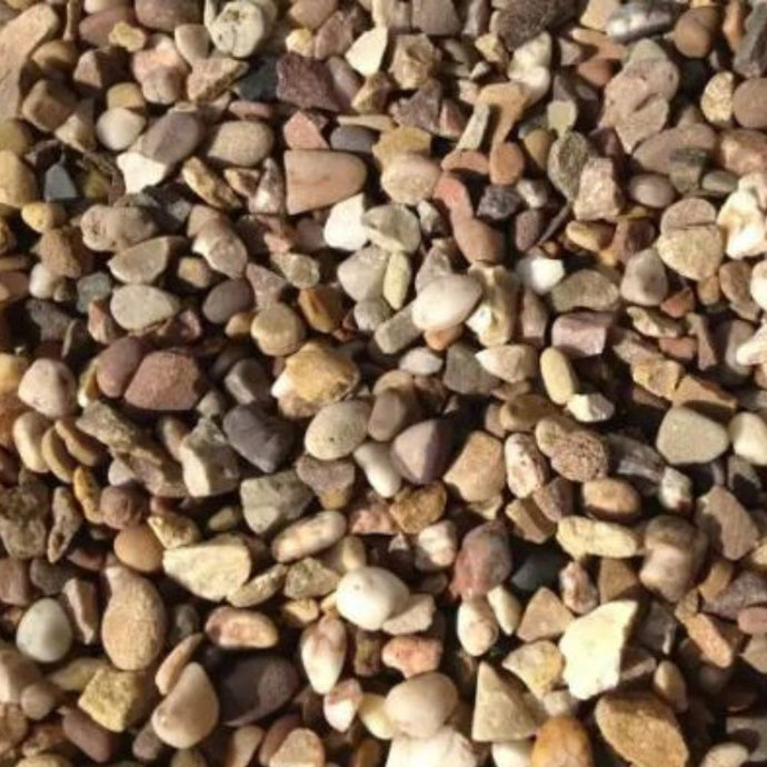 A close-up of Bingley Fencing Quartz Gravel 10mm, showing small, round and irregular pebbles in brown, tan, white, and gray hues densely covering the ground. Available in a 20kg bag for decorative aggregate use.
