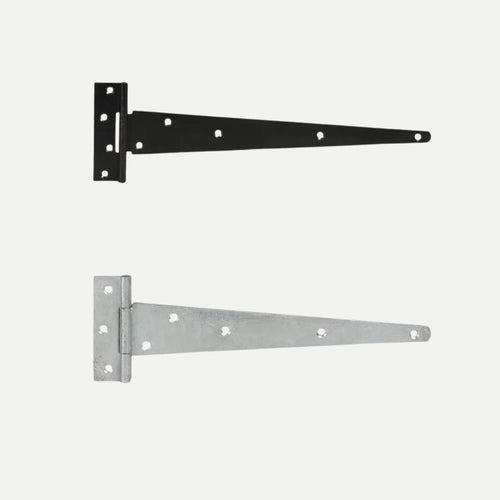 On a white backdrop, two metal T-hinges stand out: the upper hinge is a Henry Shaw Medium T Hinge, powder-coated black with eight holes, ideal for gate ironmongery. Below it lies a silver version, also from Henry Shaw, featuring seven holes. Both hinges boast a rectangular base and long, tapering strap suitable for medium T hinge applications.