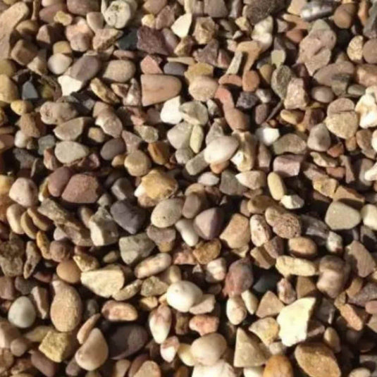 A close-up of Bingley Fencing’s Quartz Gravel 20mm 20kg Bag shows small pebbles in brown, beige, gray, and white—ideal for garden borders or as decorative gravel.