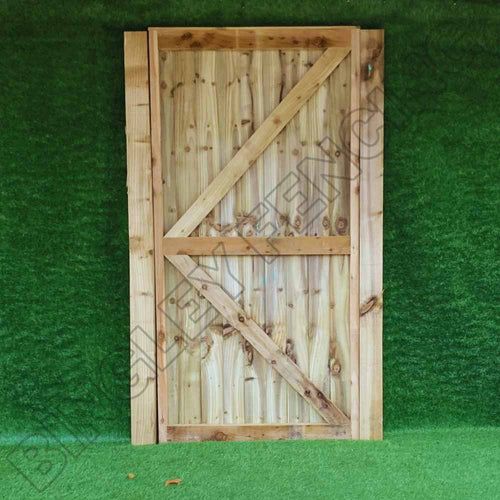 A bespoke Featheredge gate from Bingley Fencing, featuring a flat top design and diagonal bracing pattern, stands against a vibrant green artificial grass background. Crafted from light brown wood with visible knots and grain, this gate exemplifies a perfect blend of functionality and style in tailored installations.