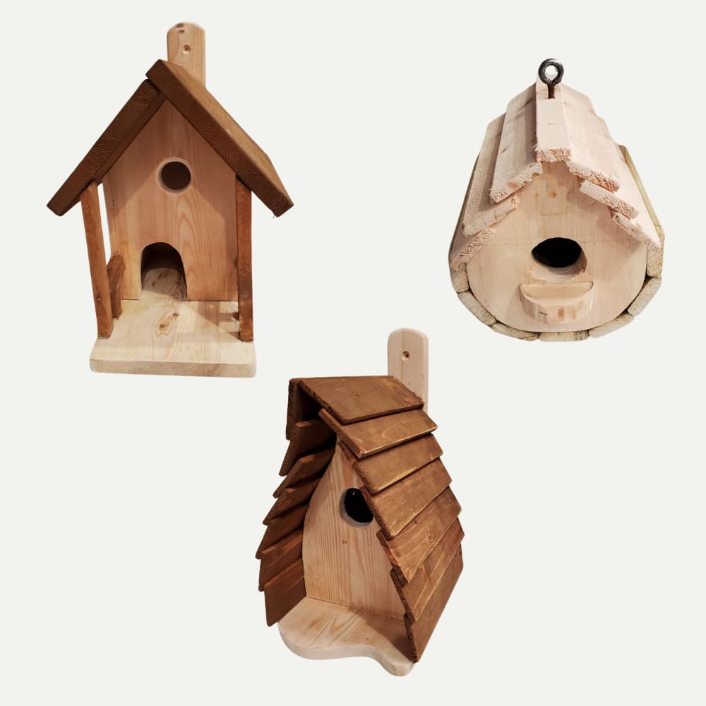 Three wooden birdhouses of different shapes and designs against a plain white background: one with a porch, one with a rounded log shape, and one with a slanted shingle roof.