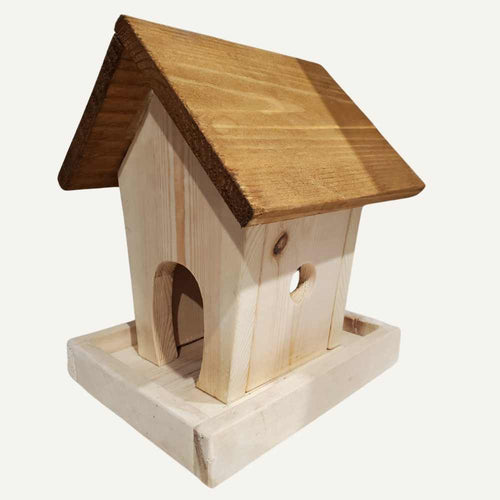 The Bingley Fencing Bird Feeder - Bird House features a simple wooden design with a slanted brown roof, arched entrance, circular window, and unique feeder on its rectangular base, all set against a plain white background.