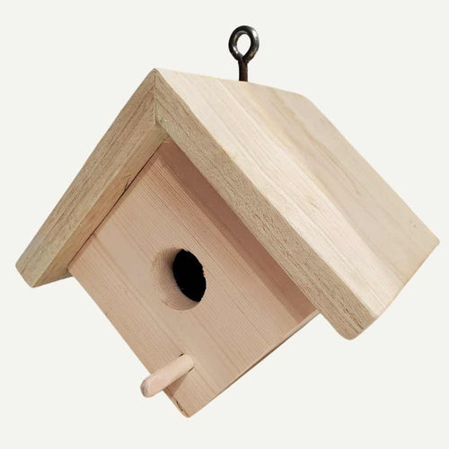 The Bingley Fencing Small Bird House is a simple, unfinished handmade birdhouse with an apex roof, round entrance hole, small perch below the hole, and hangs from a metal hook.