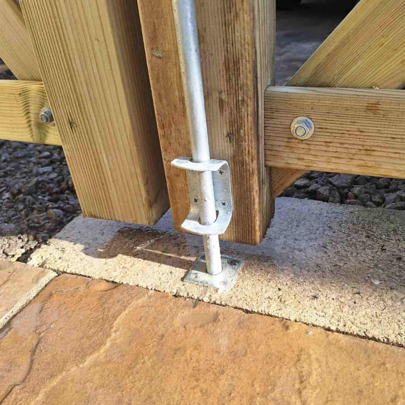 Load image into Gallery viewer, A close-up of the Henry Shaw Reduced Drop Bolt/Garage Door Bolts 12" - Black securing a wooden gate to a concrete base, with sunlight casting shadows on the ground.

