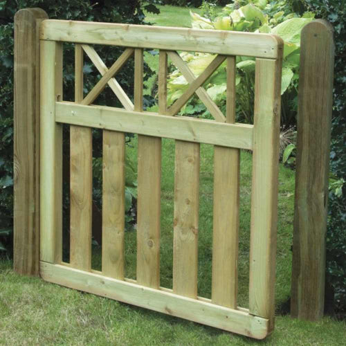 The KDM Elite Cross Top Border Gate (ECTG90) features vertical slats with X-patterns and is crafted from tanalised softwood. It’s set between sturdy posts on a lawn, enhancing the greenery backdrop and matching nearby garden border panels.