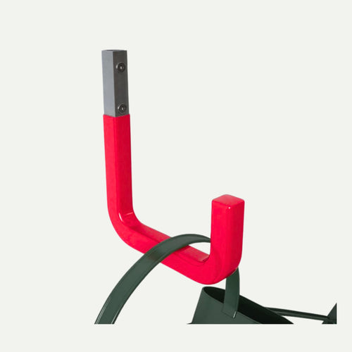 Close-up of a Rothley Steel Storage Hook in red and gray, mounted on a white wall and holding the dark green strap of a bag—ideal for wall-mounted storage and efficient garage organization. The background is plain and light-colored.