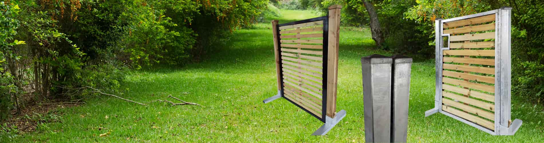 Two wooden fence panels with metal frames stand on a grassy area surrounded by green trees and bushes; two metal fence posts are also shown in the foreground.